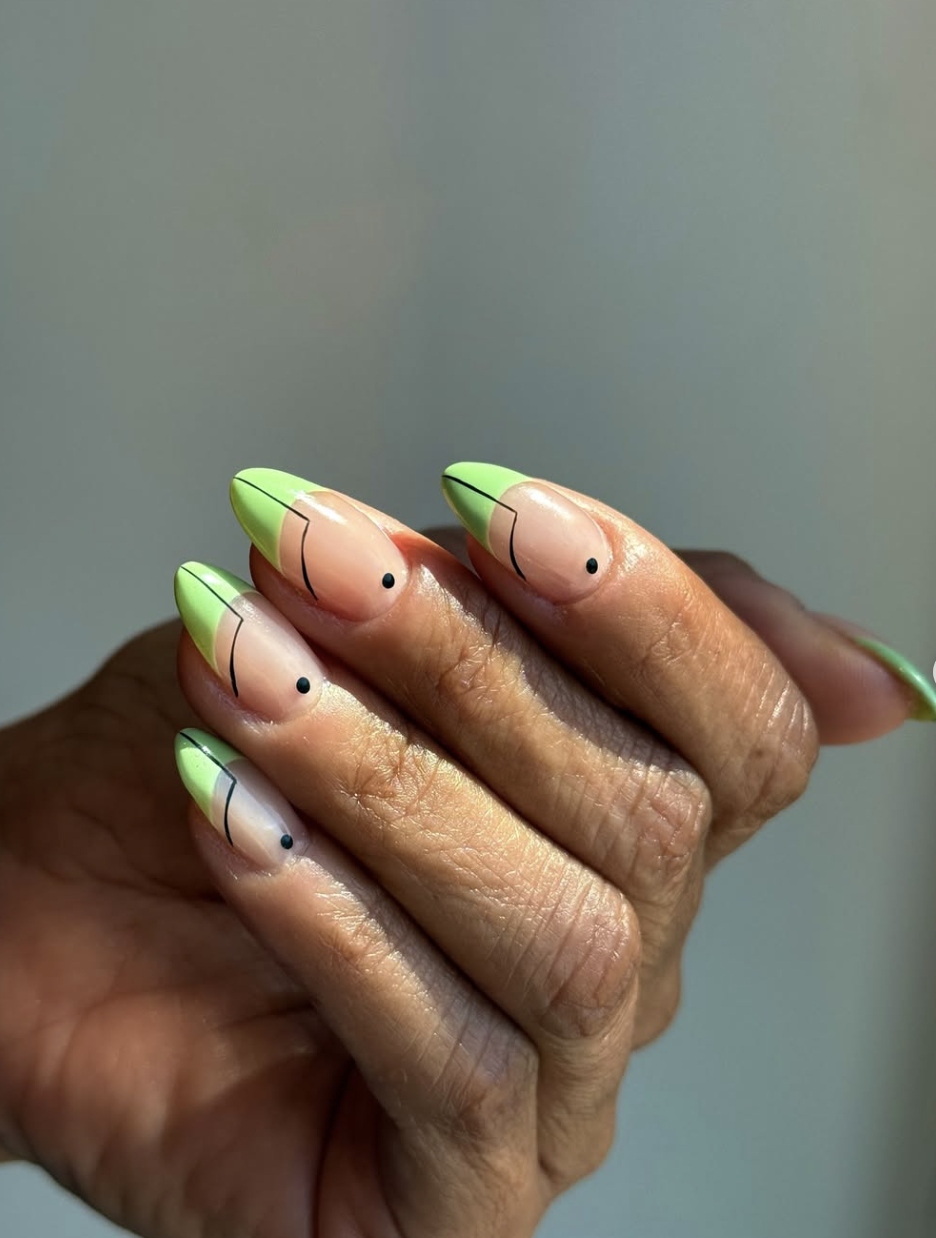 Long almond-shaped nails with a pistachio green geometric design, black line art, and minimalist dot accents.