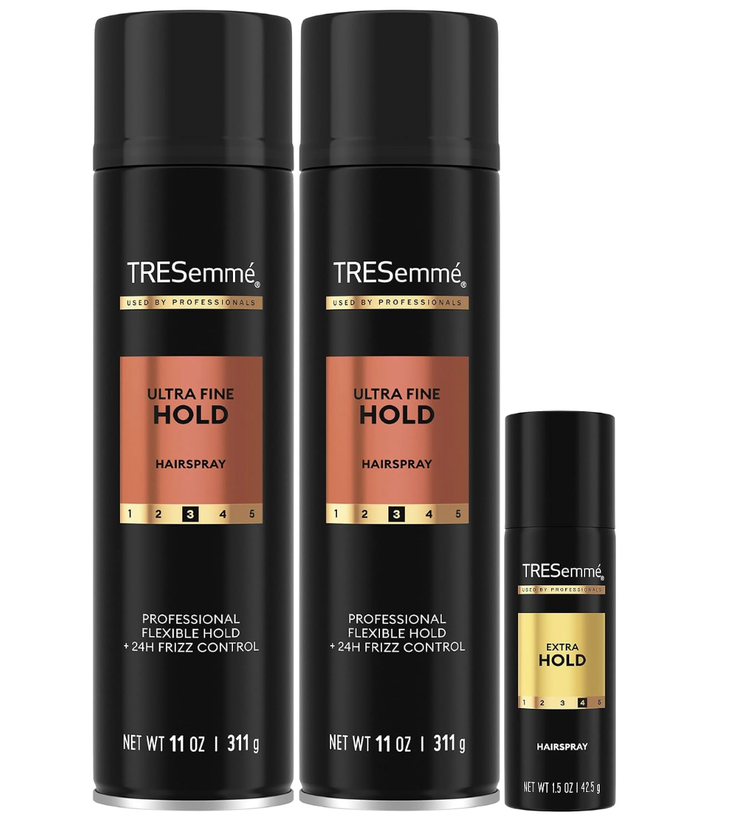 Two black cans of TRESemmé Ultra Fine Hold Hairspray next to a travel-size TRESemmé Extra Hold Hairspray.