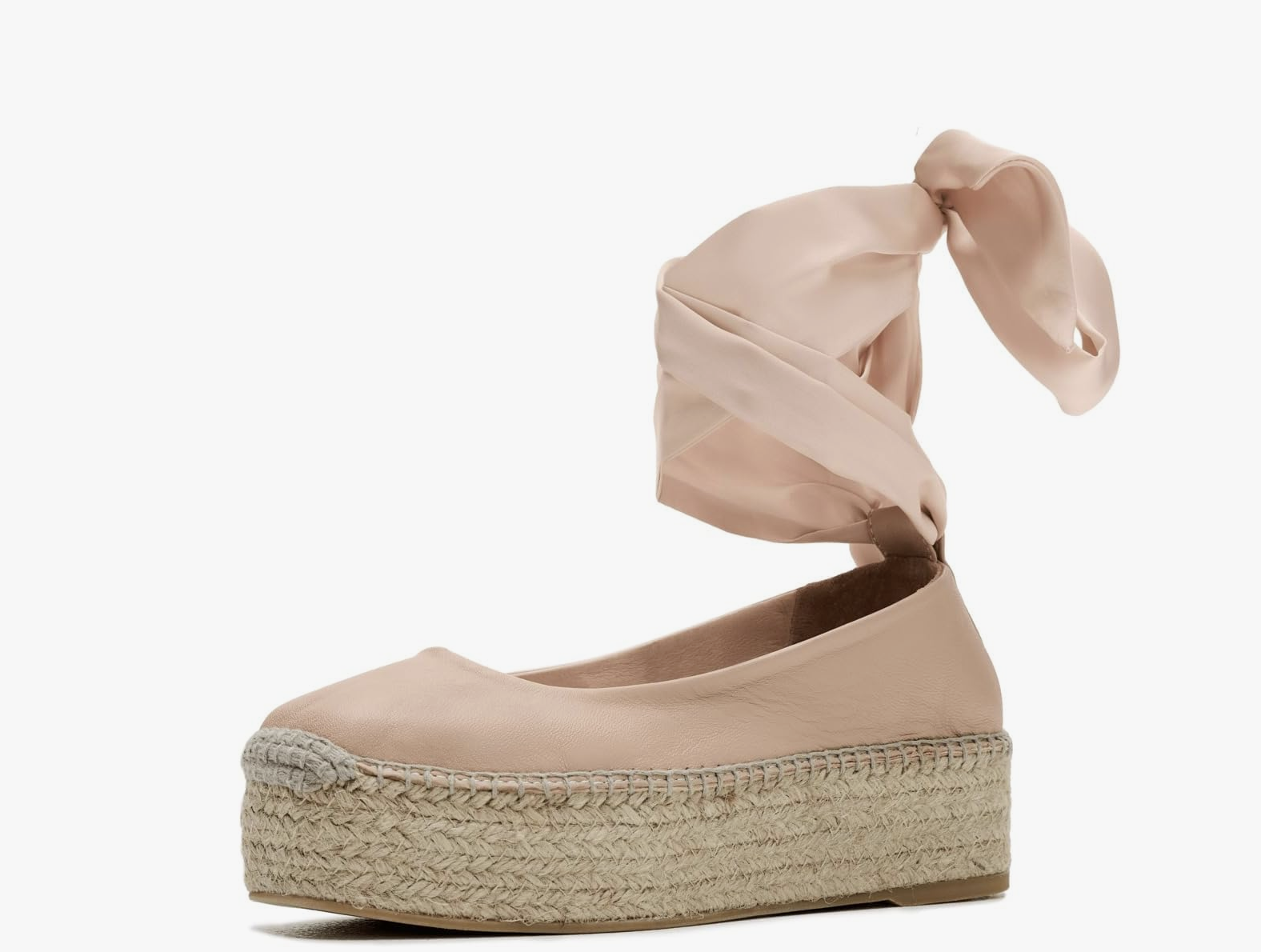 A side view of a pink leather Free People Starboard Wrap espadrille sandal with a woven jute platform and a long matching leather ankle tie on a transparent background.
