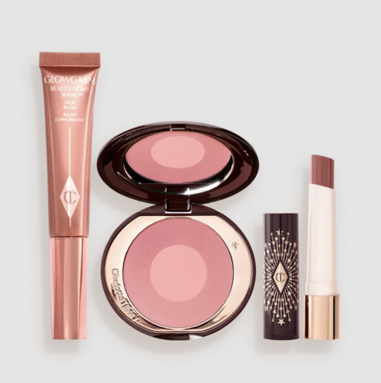 A product shot of the Charlotte Tilbury Summer Glow Lip and Cheek Kit on a white background, featuring a pink liquid blush tube, a round powder blush compact, and a hydrating lipstick balm.