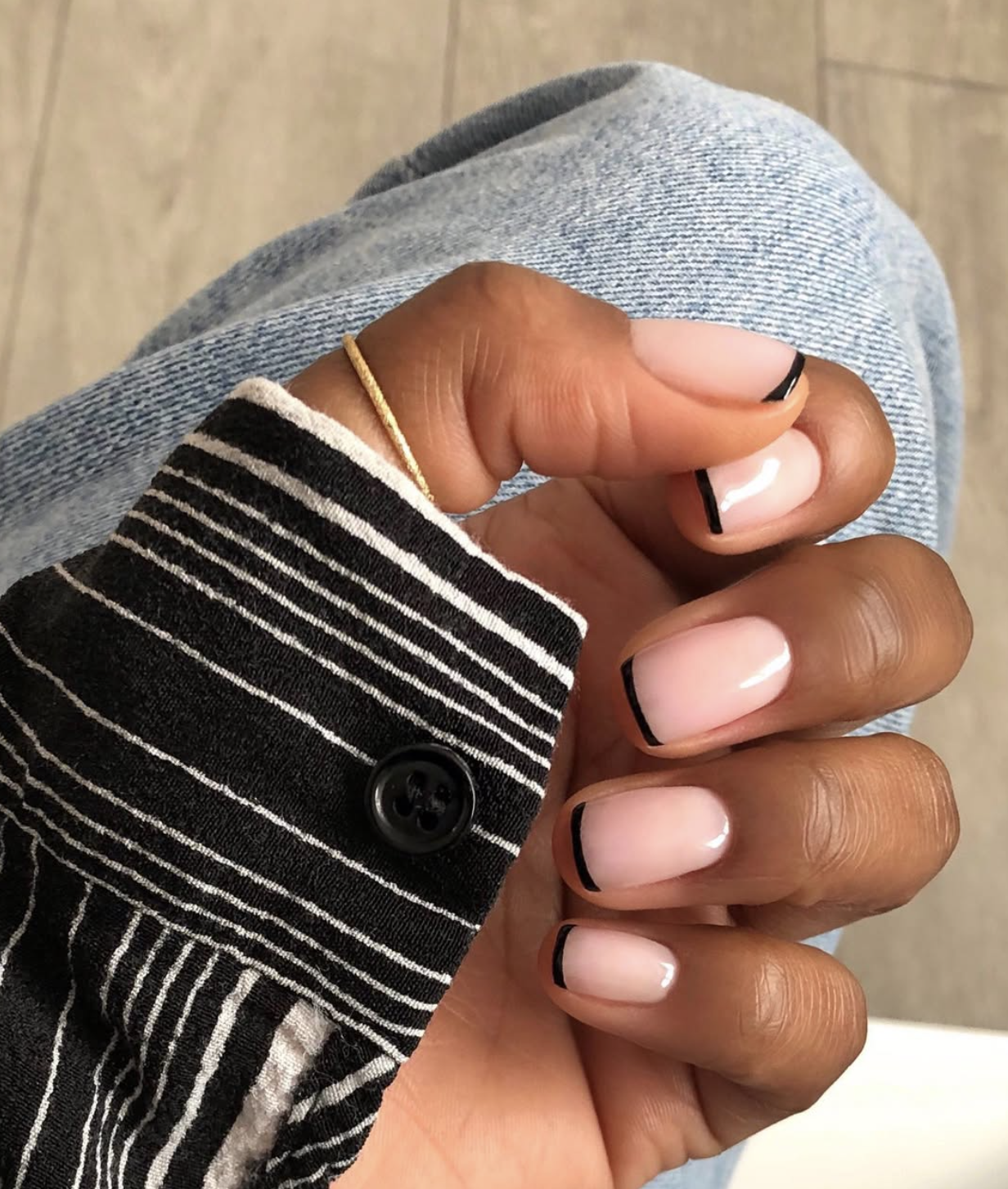 Short nails with thin black micro French tips over a sheer base