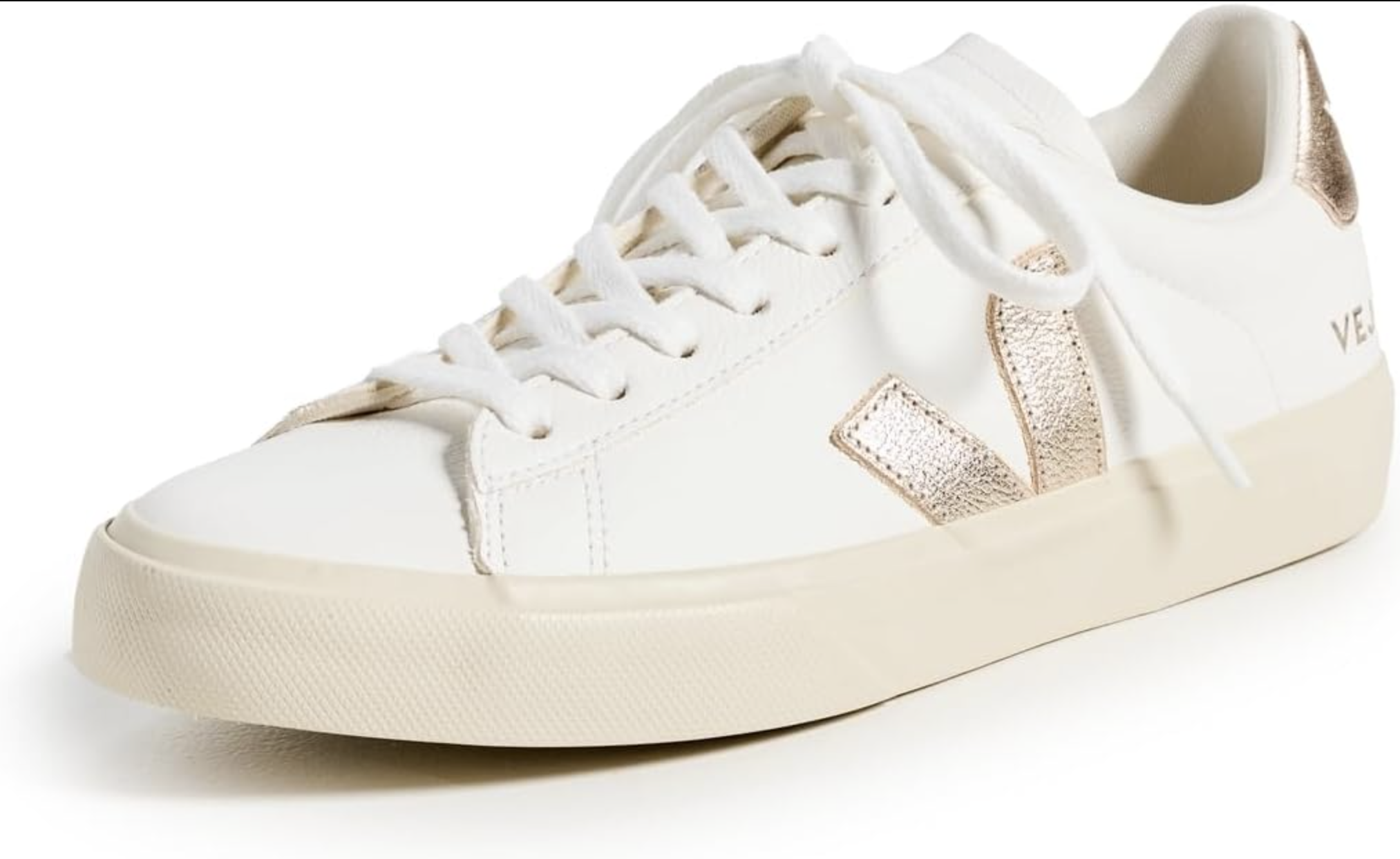 A pair of white Veja Campo leather sneakers with a beige suede 'V' logo and heel tab, styled as a versatile and comfortable walking shoe for a spring capsule wardrobe for women over 60.