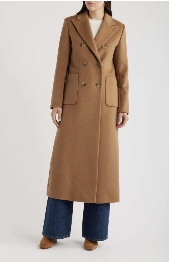 A full-length shot of a model wearing the Lauren Ralph Lauren Double-Breasted Longline Wool-Blend Coat in a rich camel brown, styled with wide-leg blue jeans and brown suede boots.