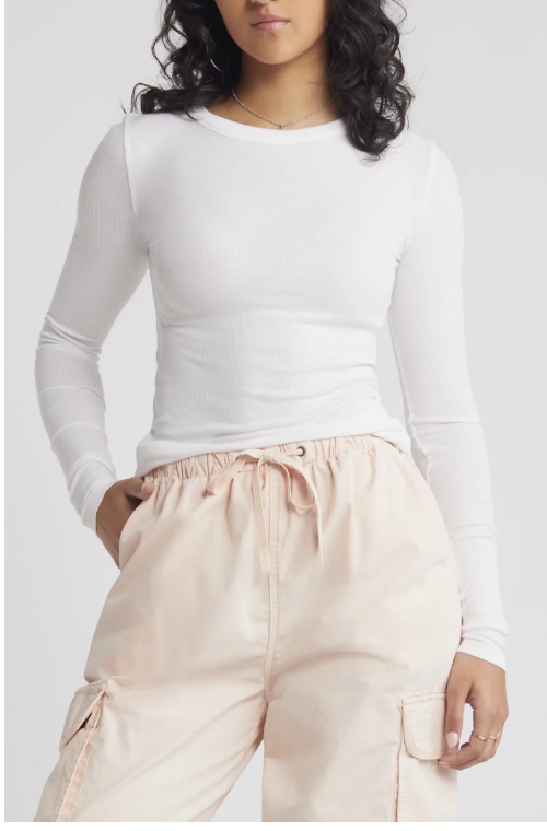 A close-up of a white BP. Ribbed Long Sleeve T-Shirt with a figure-hugging fit and crewneck, styled with high-waisted neutral joggers for a polished casual look.
