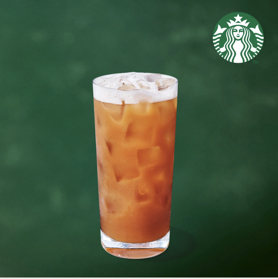 Iced Starbucks Chaider in a clear cup against a deep green background.