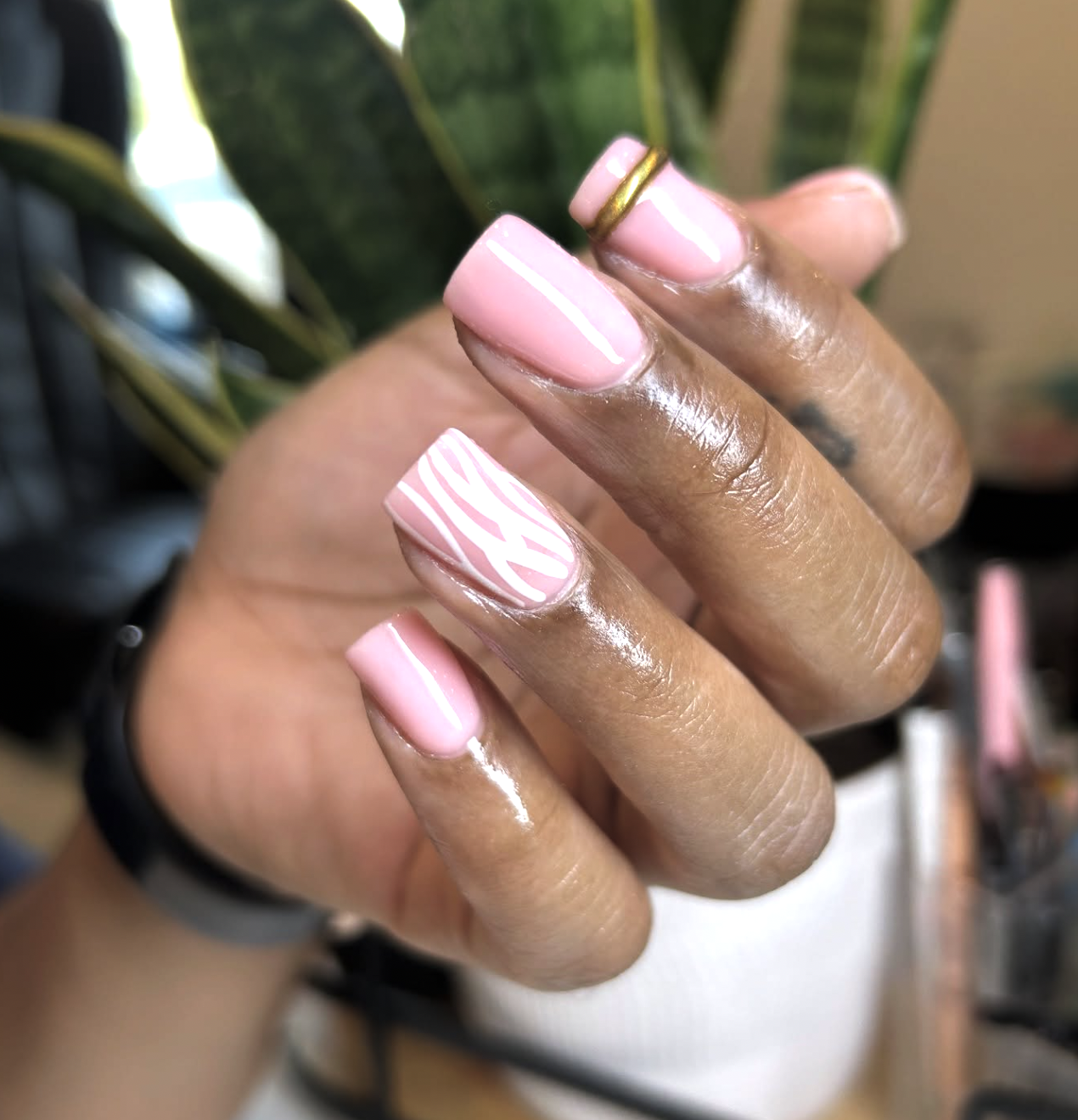 A close-up of short, square-shaped nails featuring light pink zebra print French tips on a natural base.
