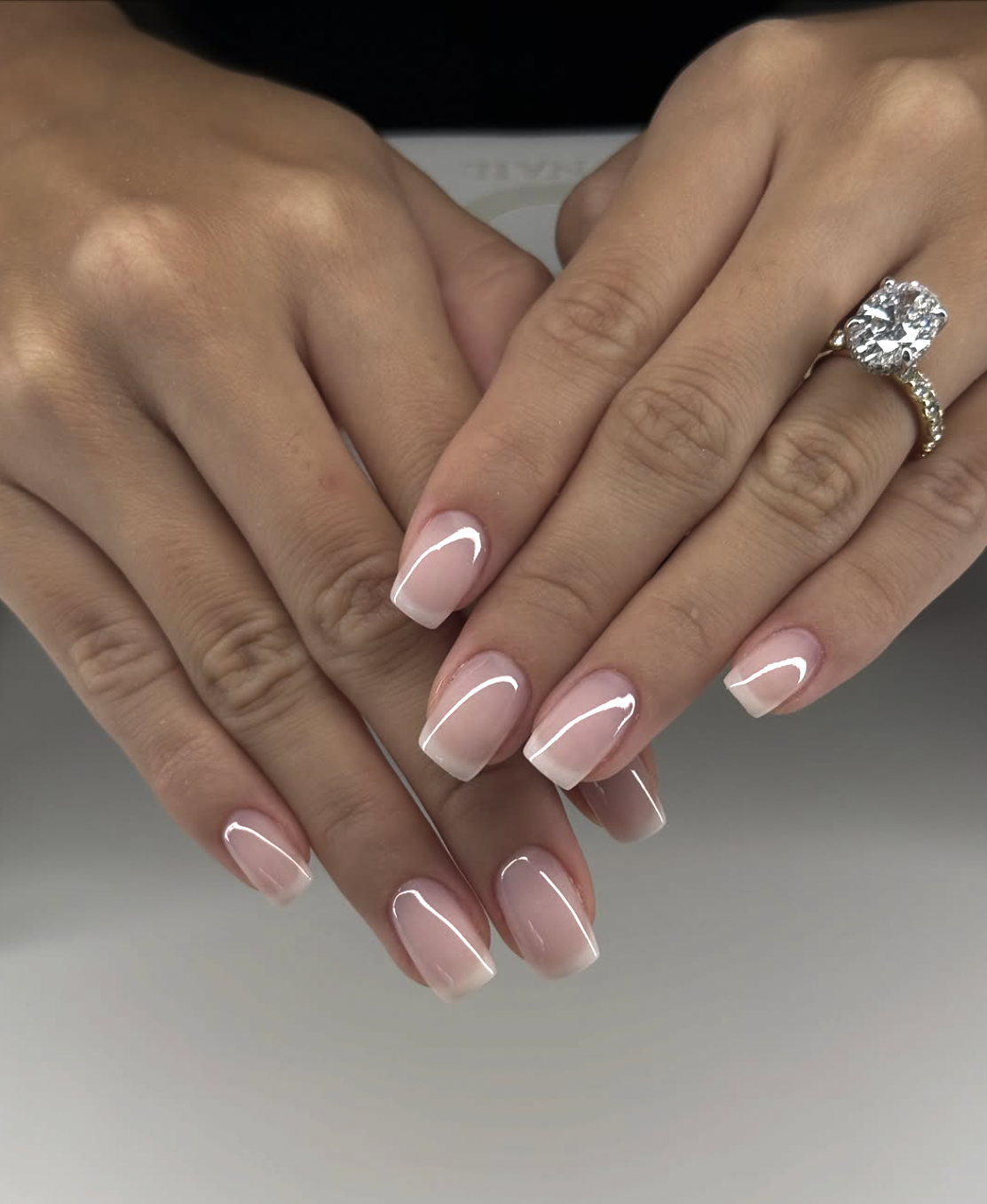 Short square-oval nails with a natural nude base and an ultra-thin, delicate white French tip.