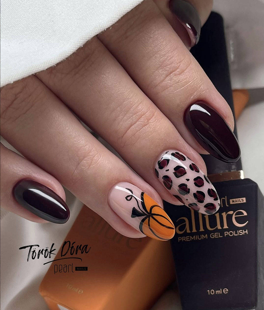 Glossy black-cherry fall nails with a terracotta pumpkin accent