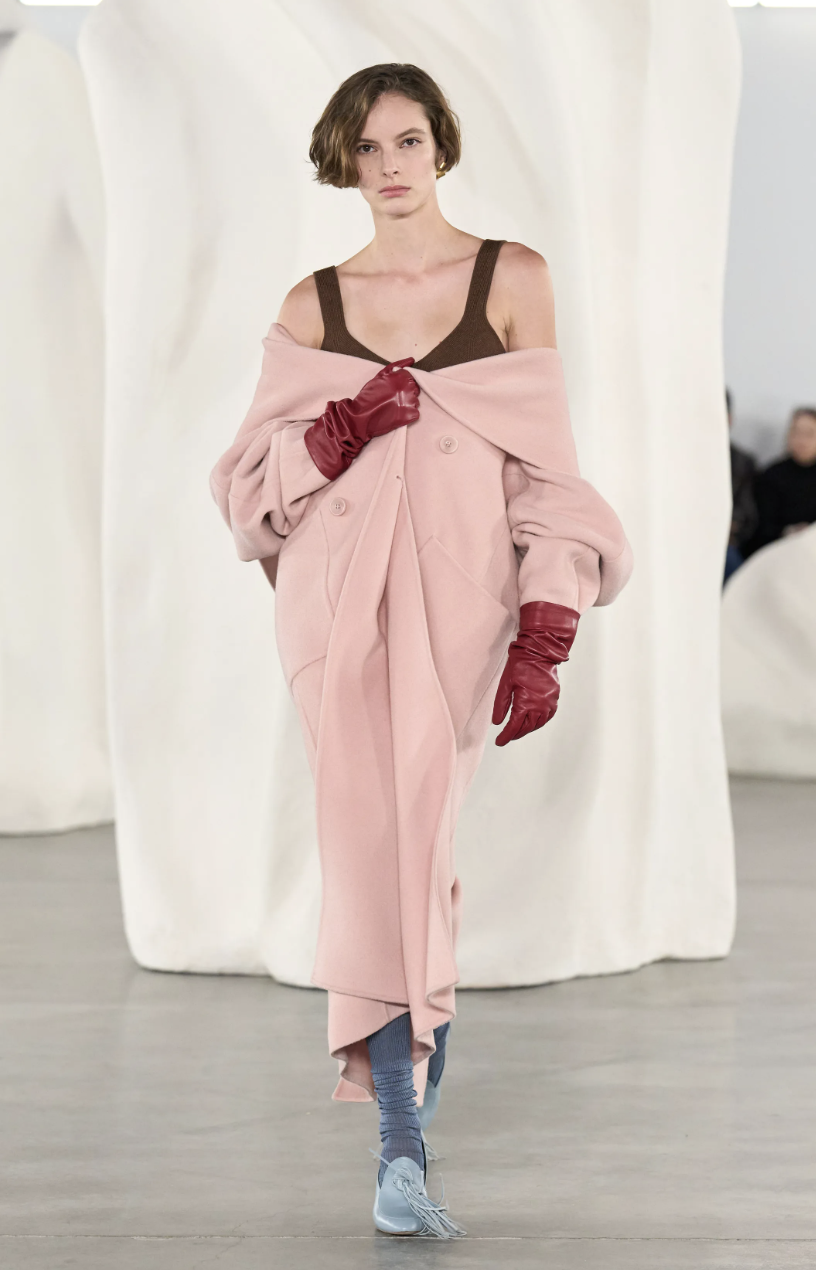 A model on the Ulla Johnson Fall/Winter 2026 runway wearing a delicate baby pink skirt paired with a chocolate brown top, illustrating the soft versus sharp color blocking trend.