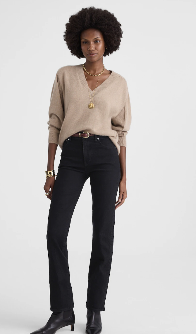 A person with an hourglass figure wearing Madewell Longline Straight jeans in a medium wash, styled with black pointed-toe heeled boots to demonstrate a leg-lengthening silhouette.