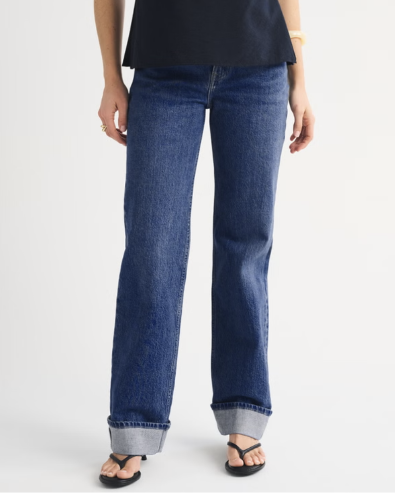 A woman wearing Abercrombie High Rise 90s Relaxed Jeans in a light blue wash with cuffed hems and black kitten heel sandals.