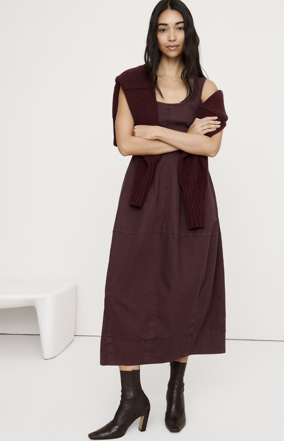 A woman wearing a dark burgundy Banana Republic Stretch-Cotton Barrel Midi Dress paired with black leather ankle boots