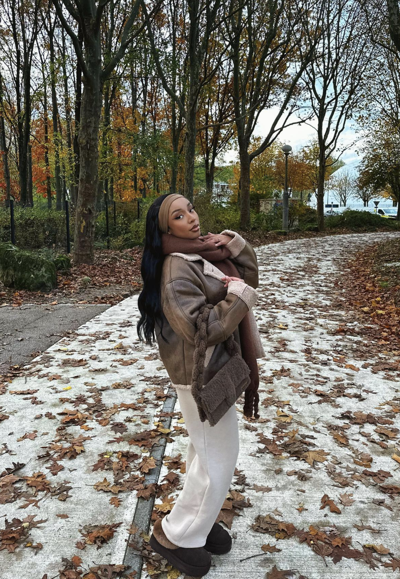 Brown shearling-trim jacket, taupe base and oversized brown scarf in an autumn setting.