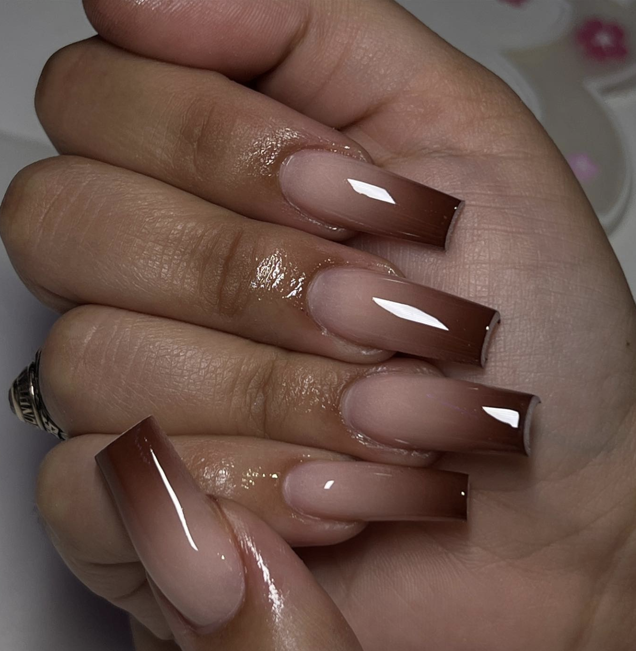 A close-up of glossy nails featuring a smooth coffee ombré gradient transitioning from a light nude base into rich chocolate brown.
