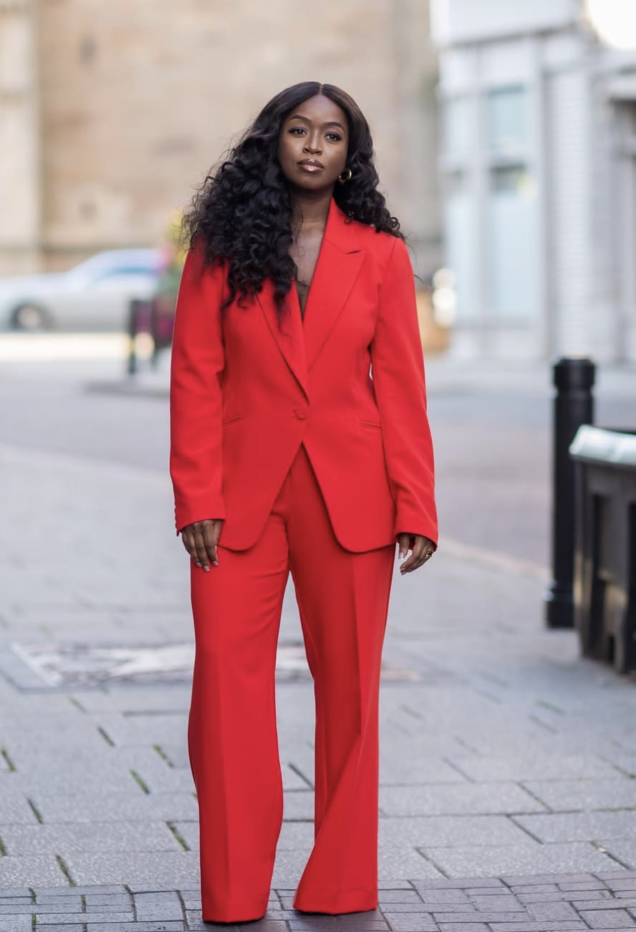A woman wearing a vibrant monochromatic red power suit with a structured blazer and matching wide-leg trousers.