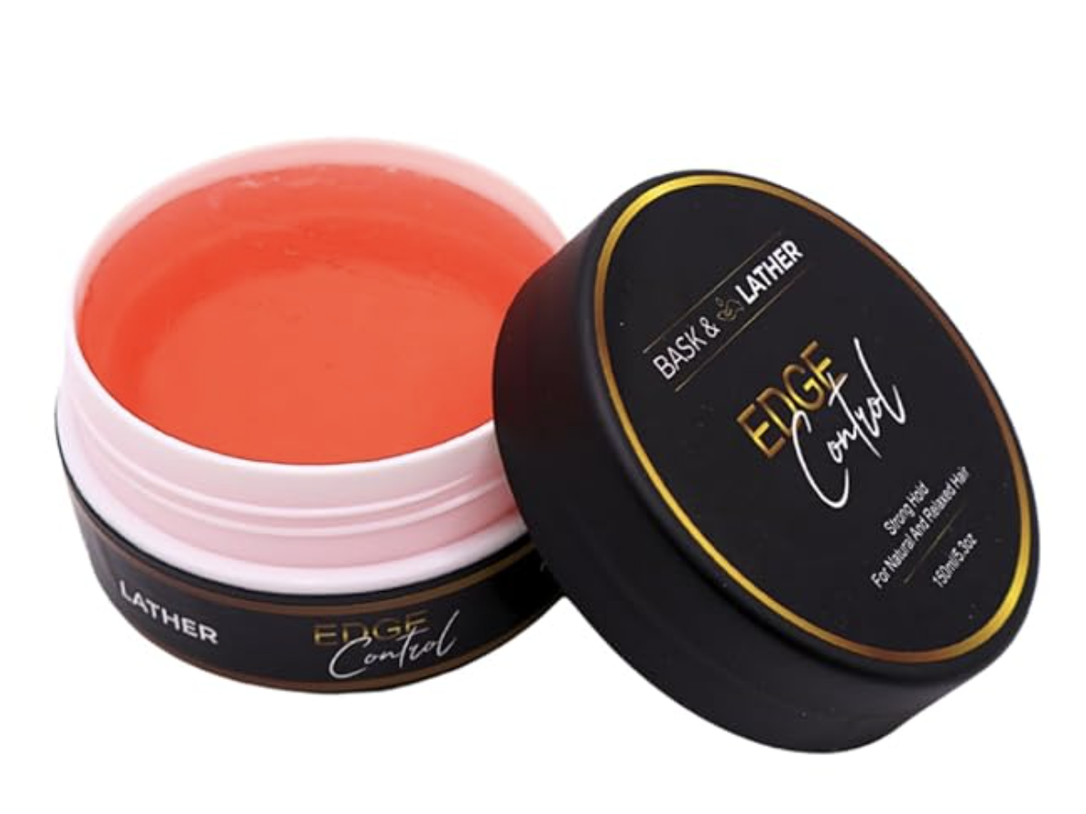 A black jar of Bask and Lather Strong Hold Edge Control next to its lid, showing the orange-tinted gel inside.