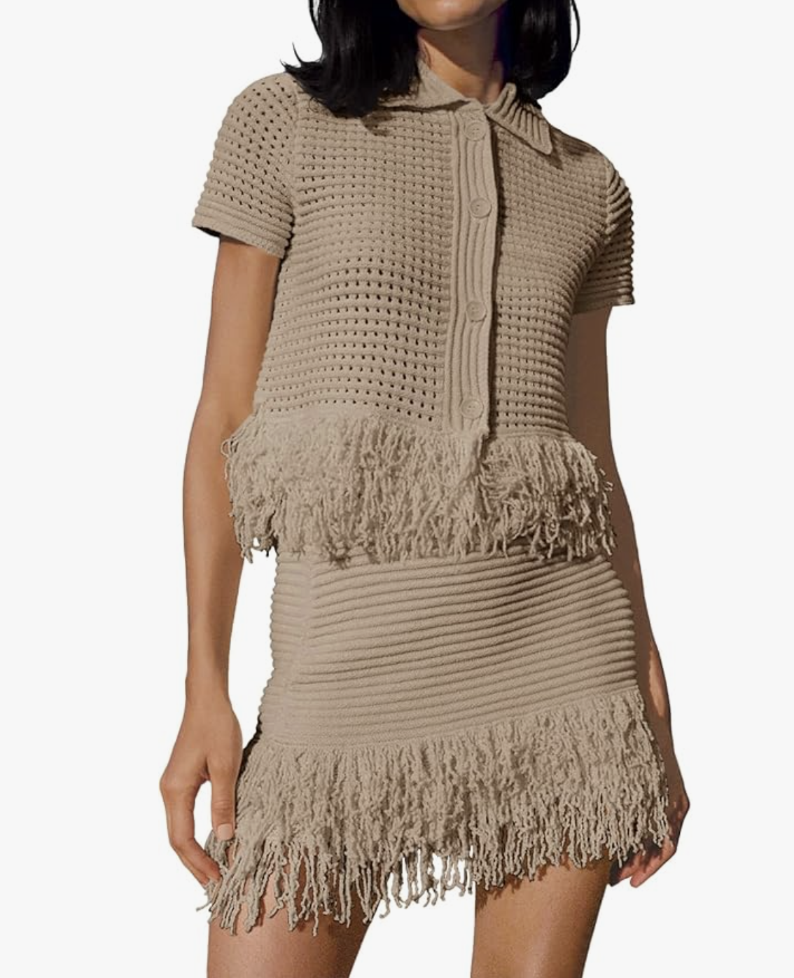 A woman wearing a beige crochet two-piece set featuring a short-sleeve button-down shirt and a matching midi skirt with long fringe trim, styled as a sophisticated vacation outfit for women in their 50s.