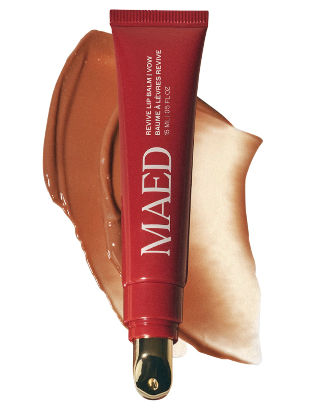 MAED Beauty Revive Lip Balm for Barrier Repair in a sleek red tube with a swatch of the rich, hydrating copper-toned balm texture on a transparent background.