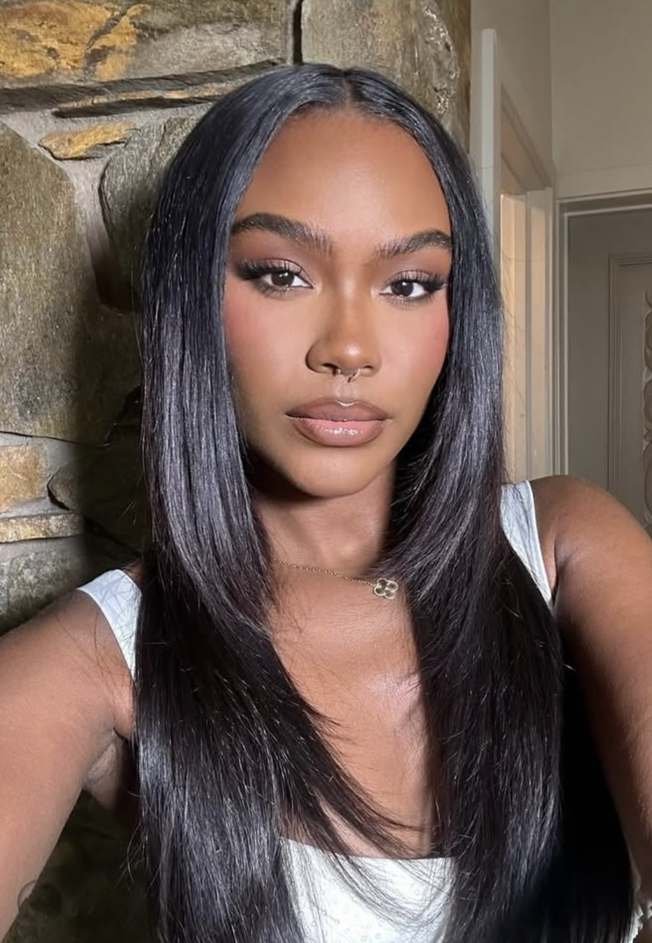 Choyce Brown wearing a sleek silk press with straight, voluminous hair and a middle part to frame an oval face shape.