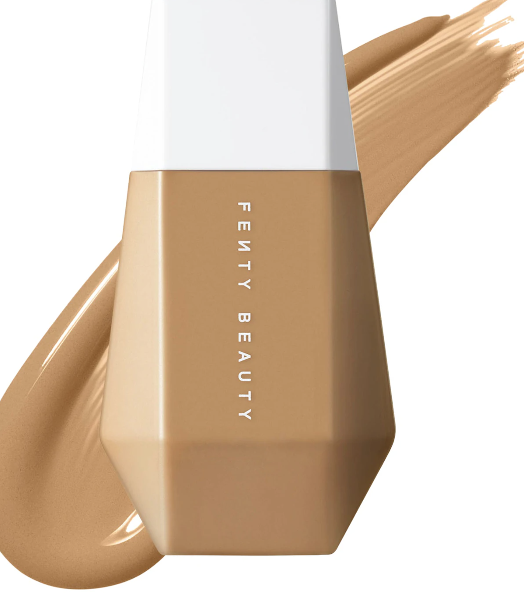 A tan-colored bottle of Fenty Beauty Eaze Drop Blurring Skin Tint with a drop of the liquid foundation formula swatched next to it.