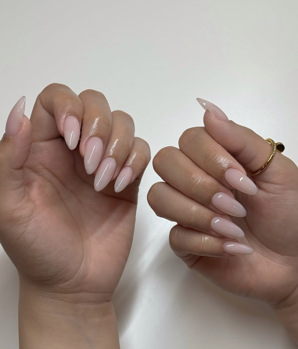 Long almond shaped nails with a semi-sheer milky pink gel polish and a high-gloss finish.