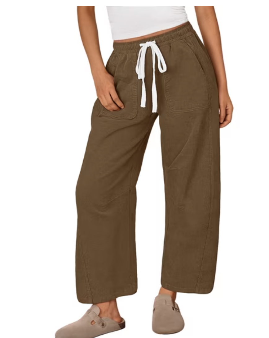 Woman wearing chocolate brown wide-leg corduroy pants with a white drawstring, a white top and taupe suede clogs.