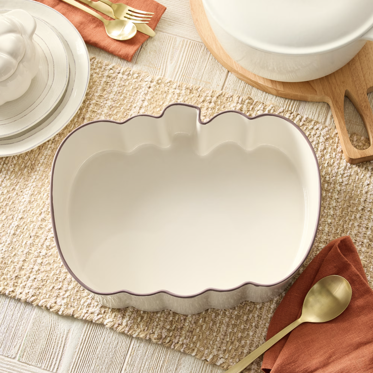 Small pumpkin-shaped stoneware cocottes filled with individual Friendsgiving side dishes