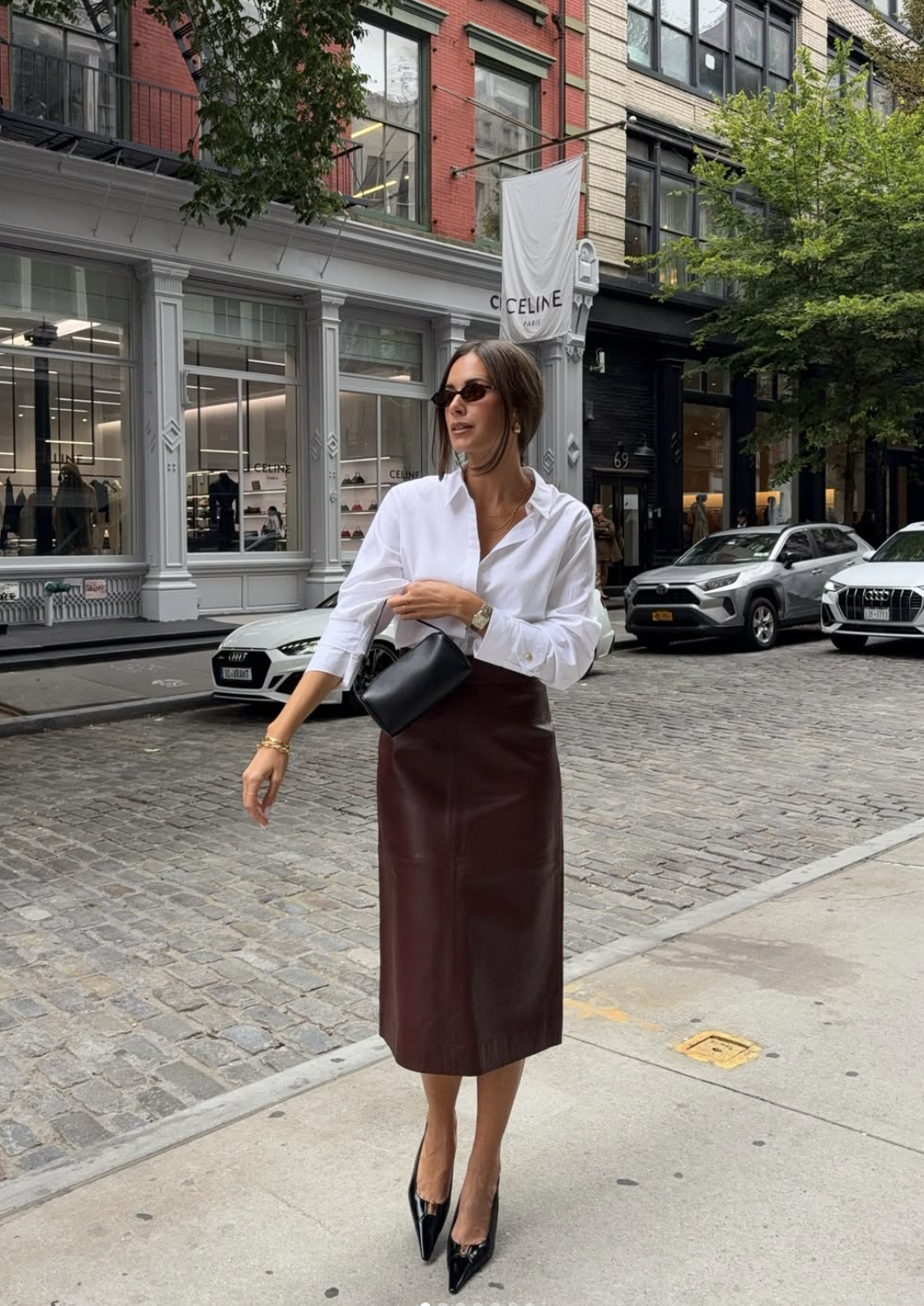 Woman wearing a burgundy leather midi pencil skirt with an oversized white shirt and black pointed pumps
