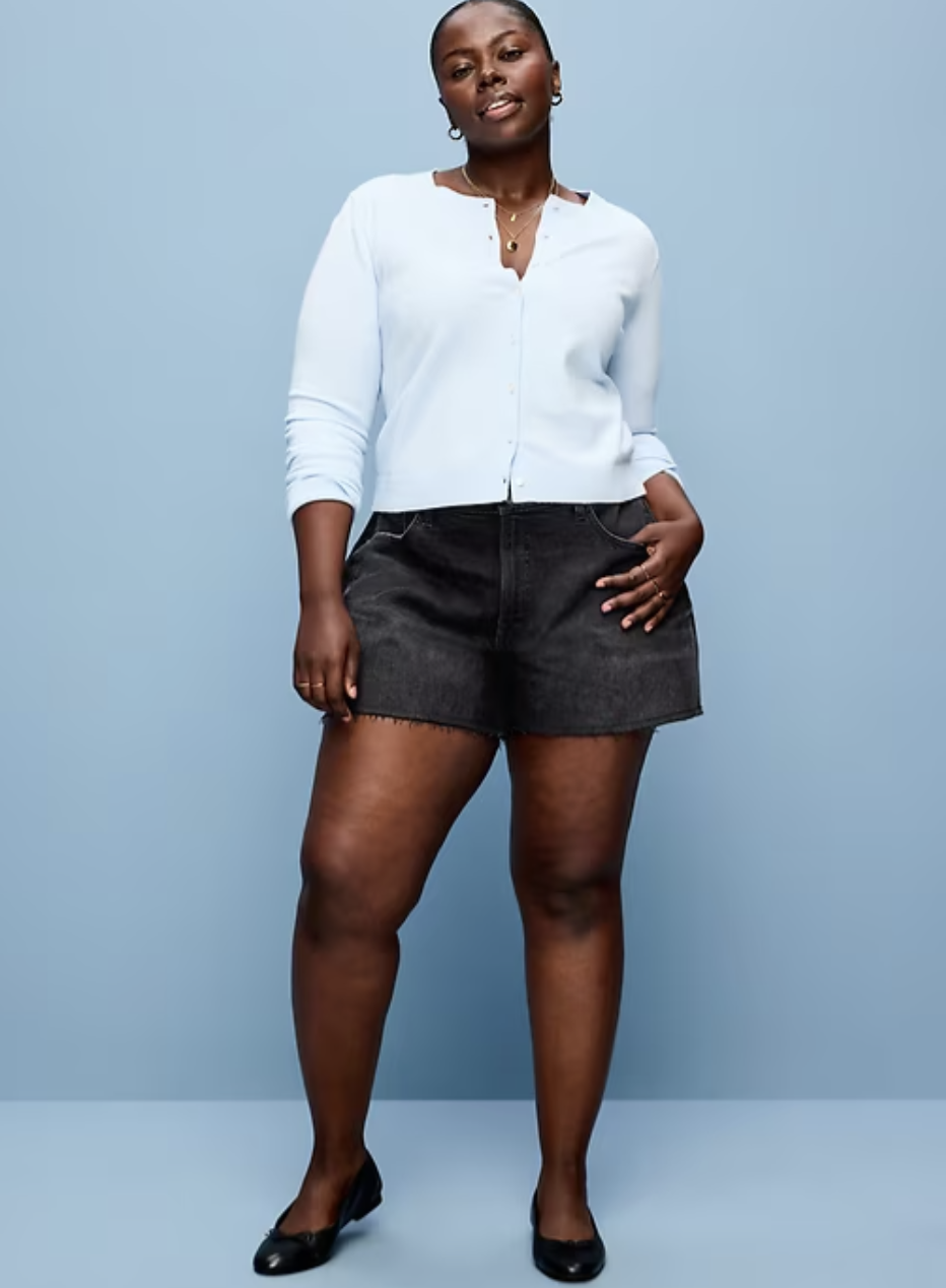 A woman wearing dark-wash Old Navy Curvy OG high-waisted jean cut-off shorts with a 4-inch inseam, designed to stay in place on thick thighs.