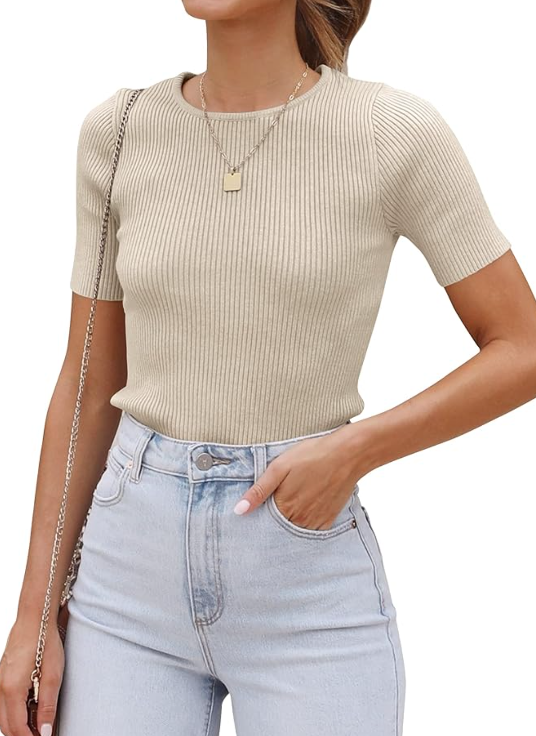 A woman wearing a taupe short-sleeve ribbed knit crewneck sweater tucked into light-wash high-waisted jeans, styled as a comfortable and professional office staple.