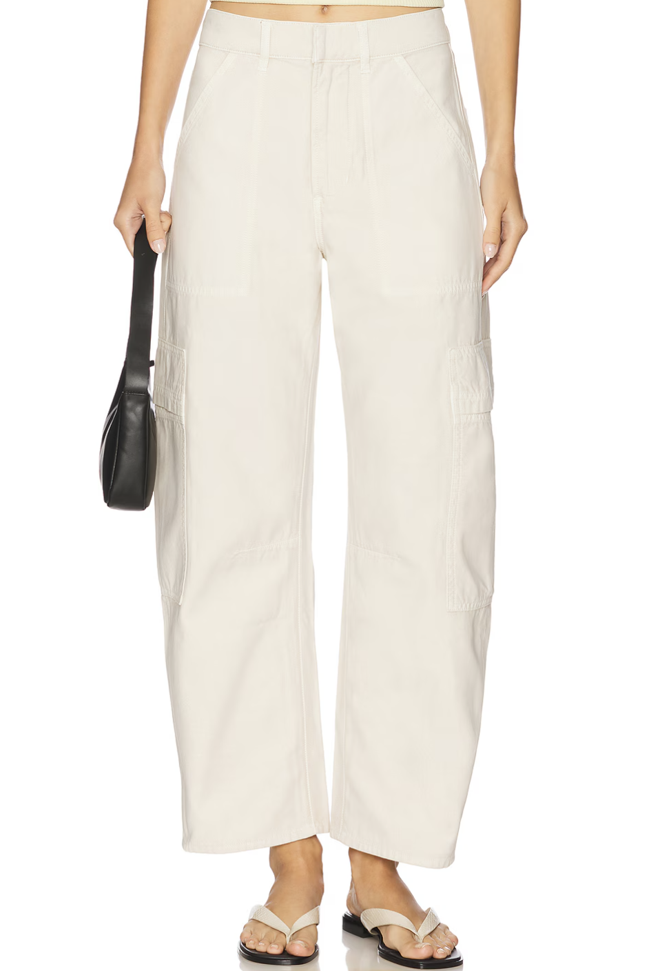 A pair of high-waisted, wide-leg cream-colored cargo pants from Citizens of Humanity, paired with minimalist white strappy sandals and a black handbag.