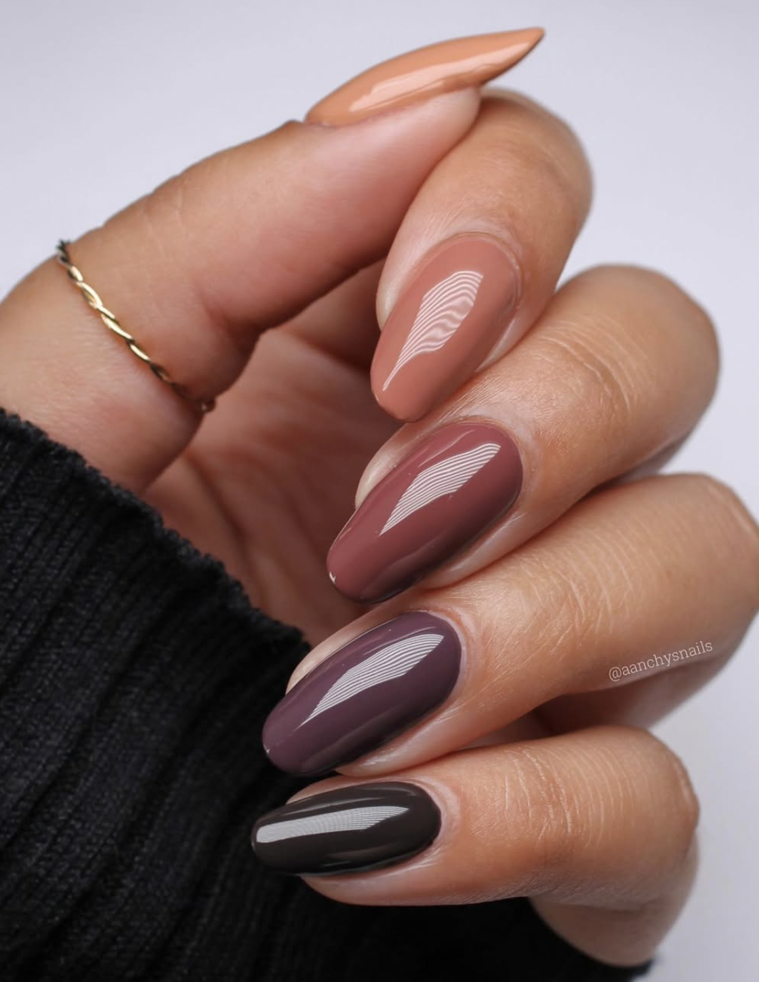 Five nails painted in different coordinated earth tones including taupe, olive, caramel and brown.