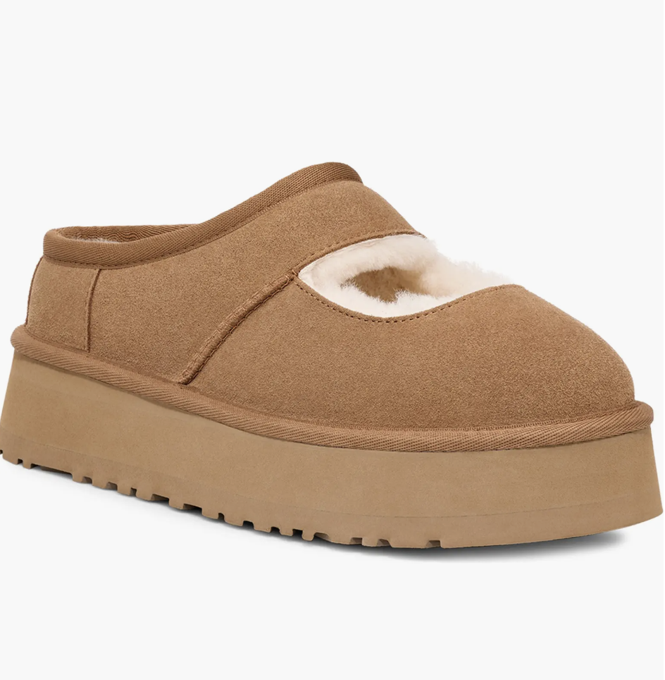 A tan suede platform Mary Jane flat for women by Ugg, featuring a thick lug sole, genuine shearling lining, and a single strap with a metal buckle.