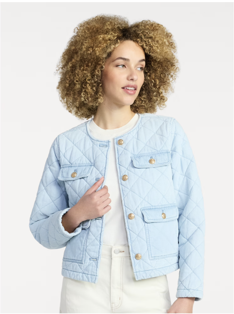 A woman wearing a light blue quilted cotton jacket with gold-tone crest buttons and patch pockets, styled over a white top and off-white trousers.