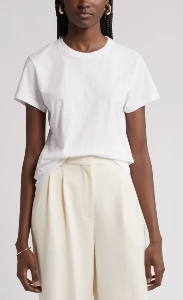 Close-up of a white cotton slub crewneck t-shirt styled with cream pleated trousers and gold hoop earrings.