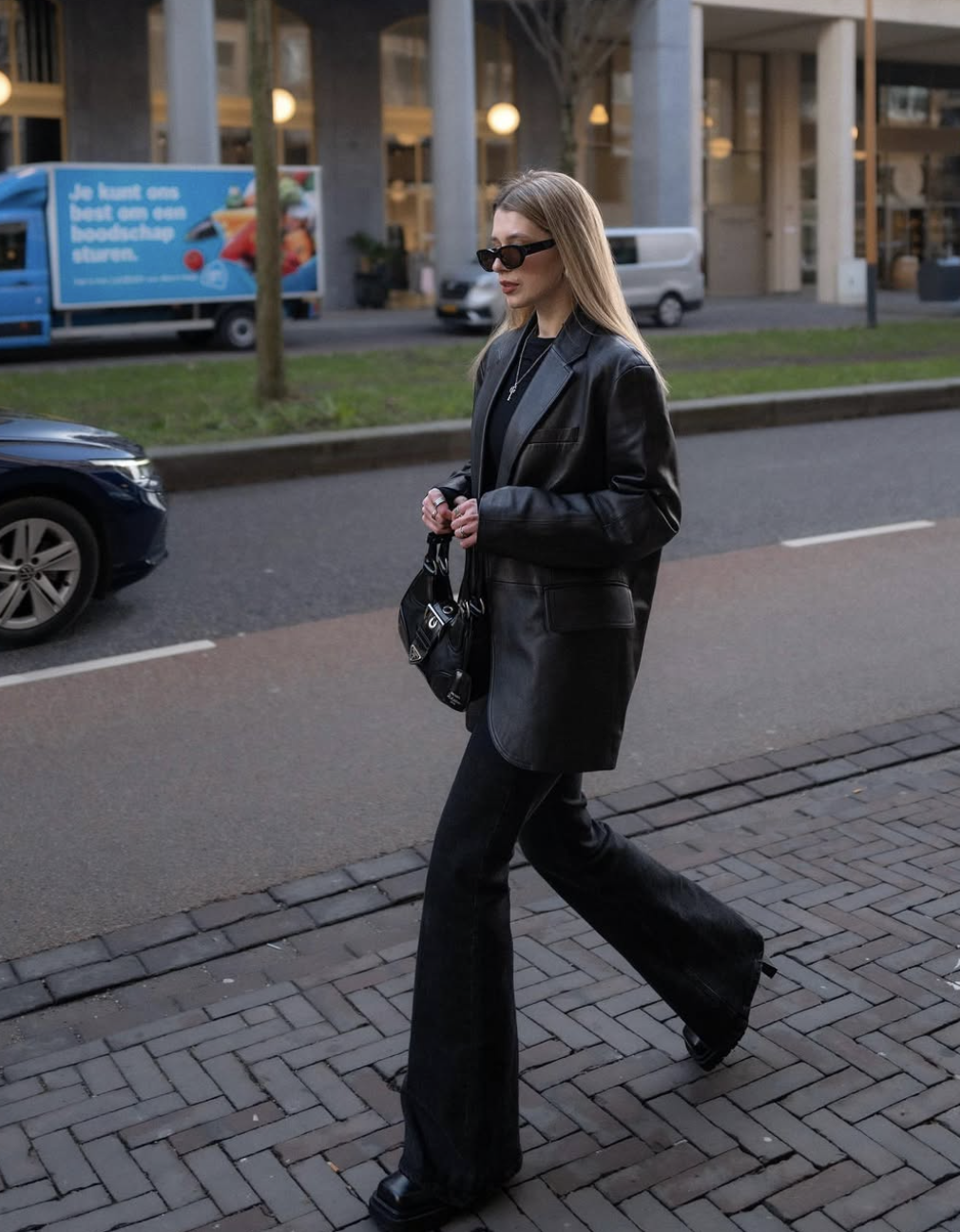 Fashion influencer wearing a structured black leather blazer over an all-black outfit with bootcut jeans and chunky platform boots.