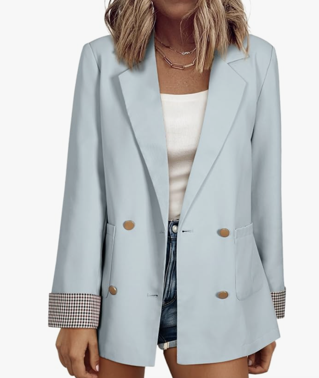 A studio product shot of a light blue double-breasted blazer from Amazon, featuring plaid-lined cuffs that are folded back, styled with a white top and denim shorts.