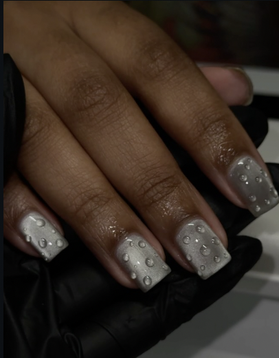Close-up of short square nails featuring a glossy slate gray manicure with clear droplet accents.