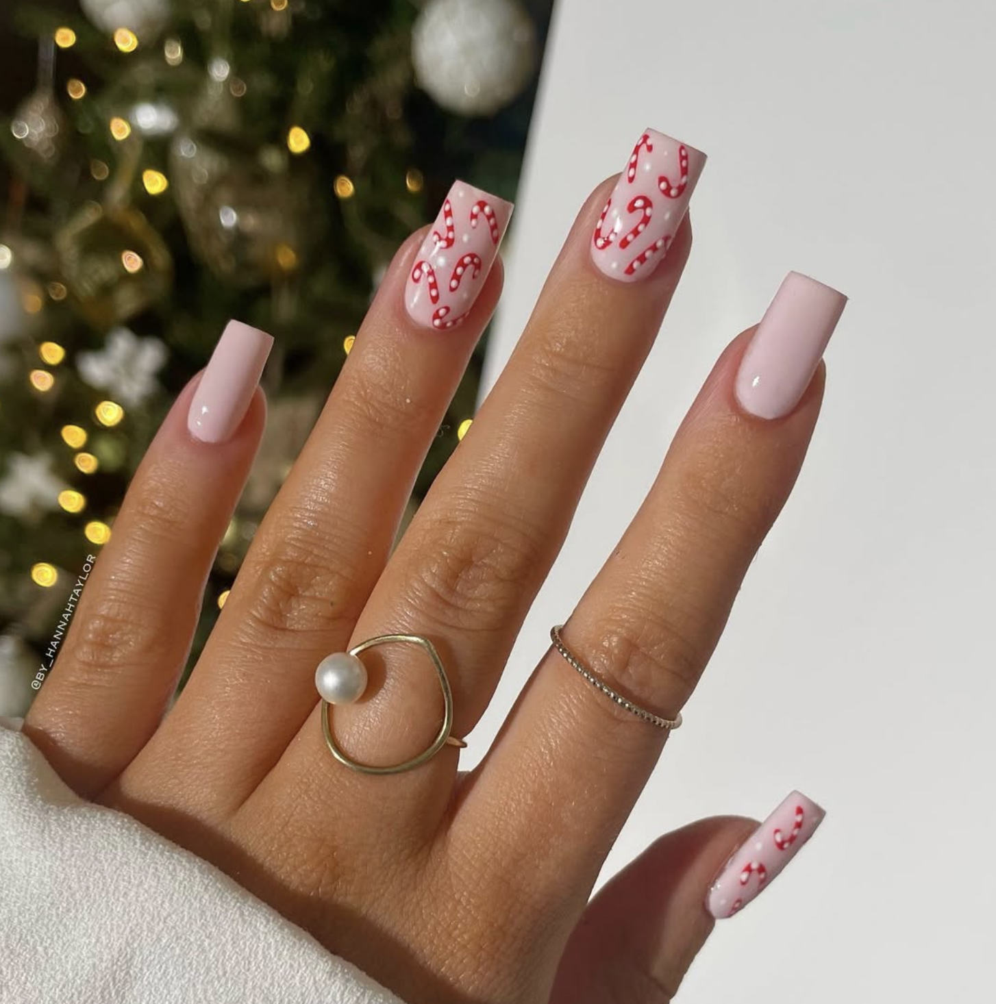 Tiny red and white candy cane nail art on a sheer milky manicure