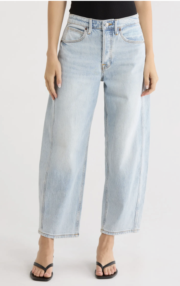 Woman wearing Good American high-waist ankle barrel jeans with a curved leg and cropped hem.