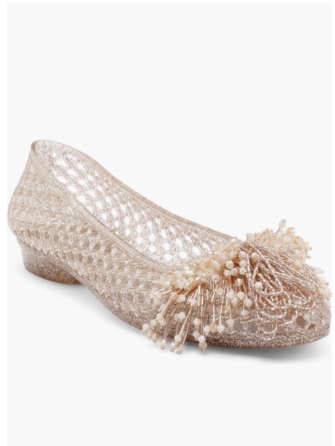 A close-up product view of a light pink woven mesh-style jelly flat shoe featuring a rounded toe and a flexible lattice knit pattern on a white background.