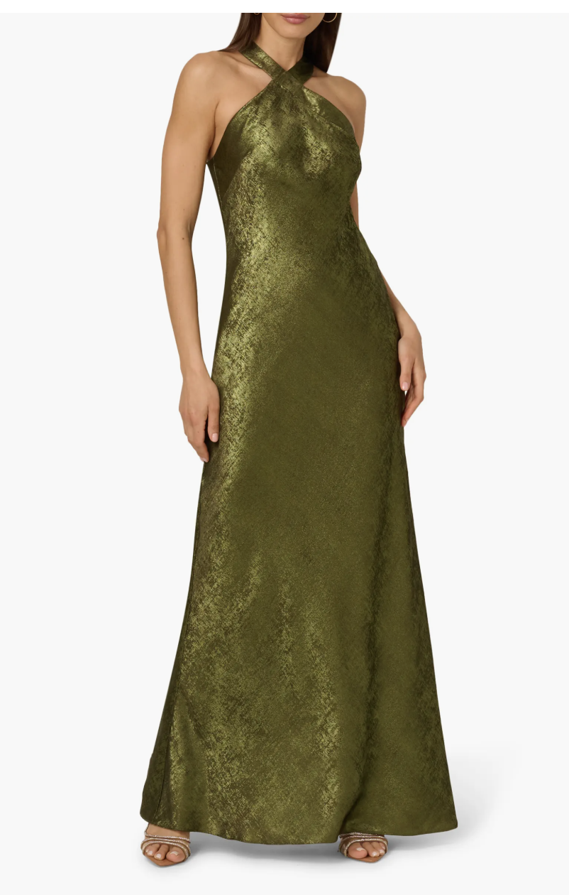 A woman wearing a gold Adrianna Papell Foiled Trumpet Gown with a metallic finish and dramatic cape detail.