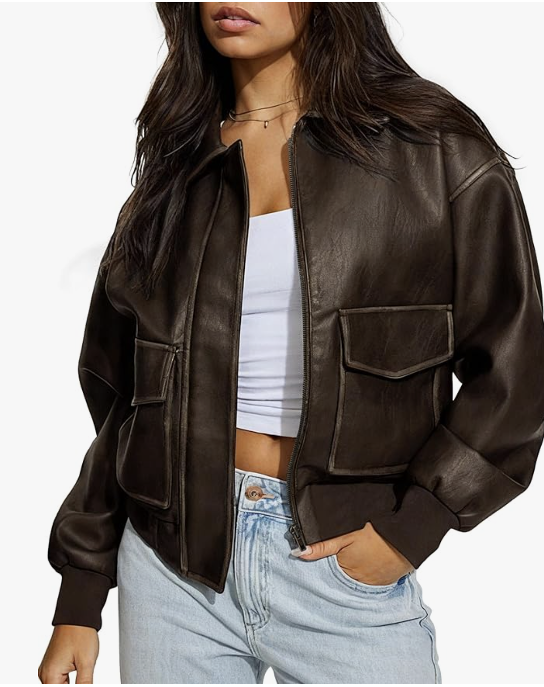 Woman wearing a chocolate brown cropped faux leather jacket with large front utility pockets and a silver zipper, paired with light wash jeans.