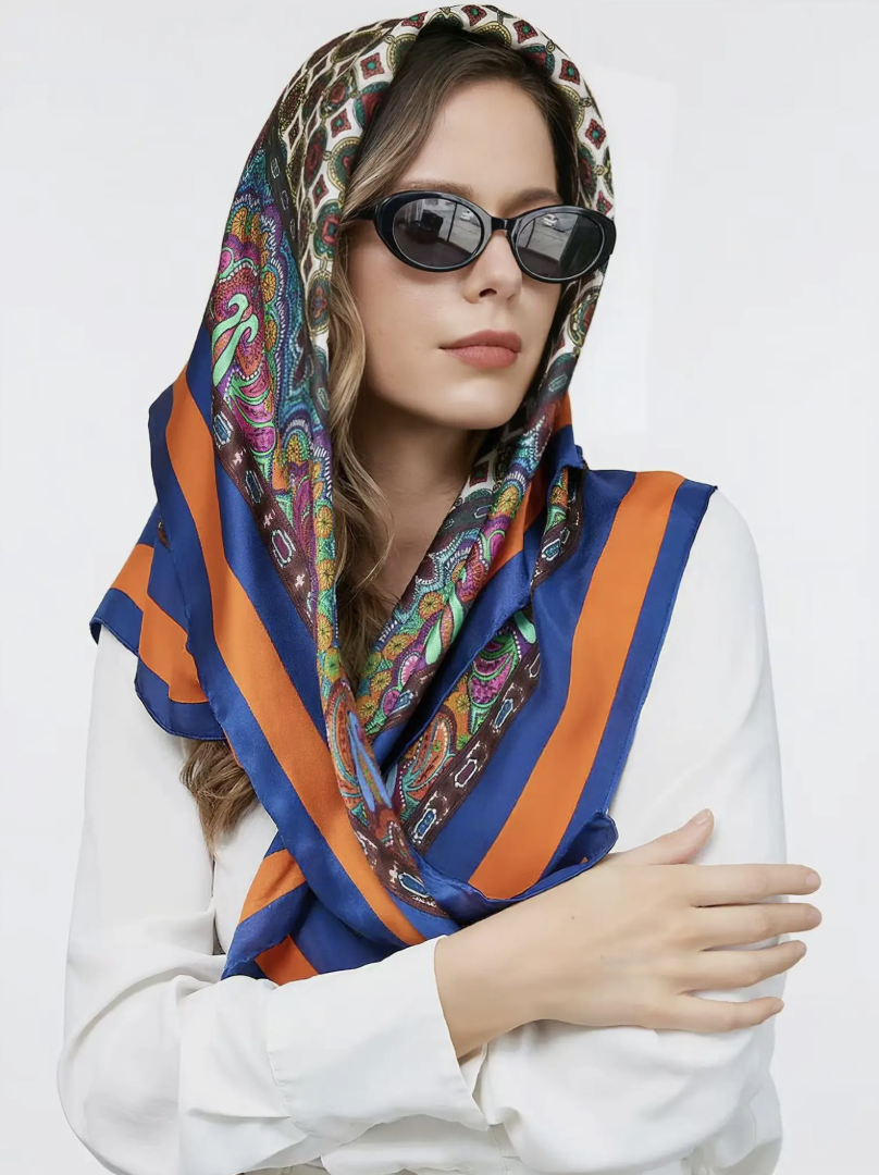 A woman wearing a Pure Silk Bohemian Square Scarf styled over her head with black oval sunglasses, showcasing a classic understated luxury accessory.