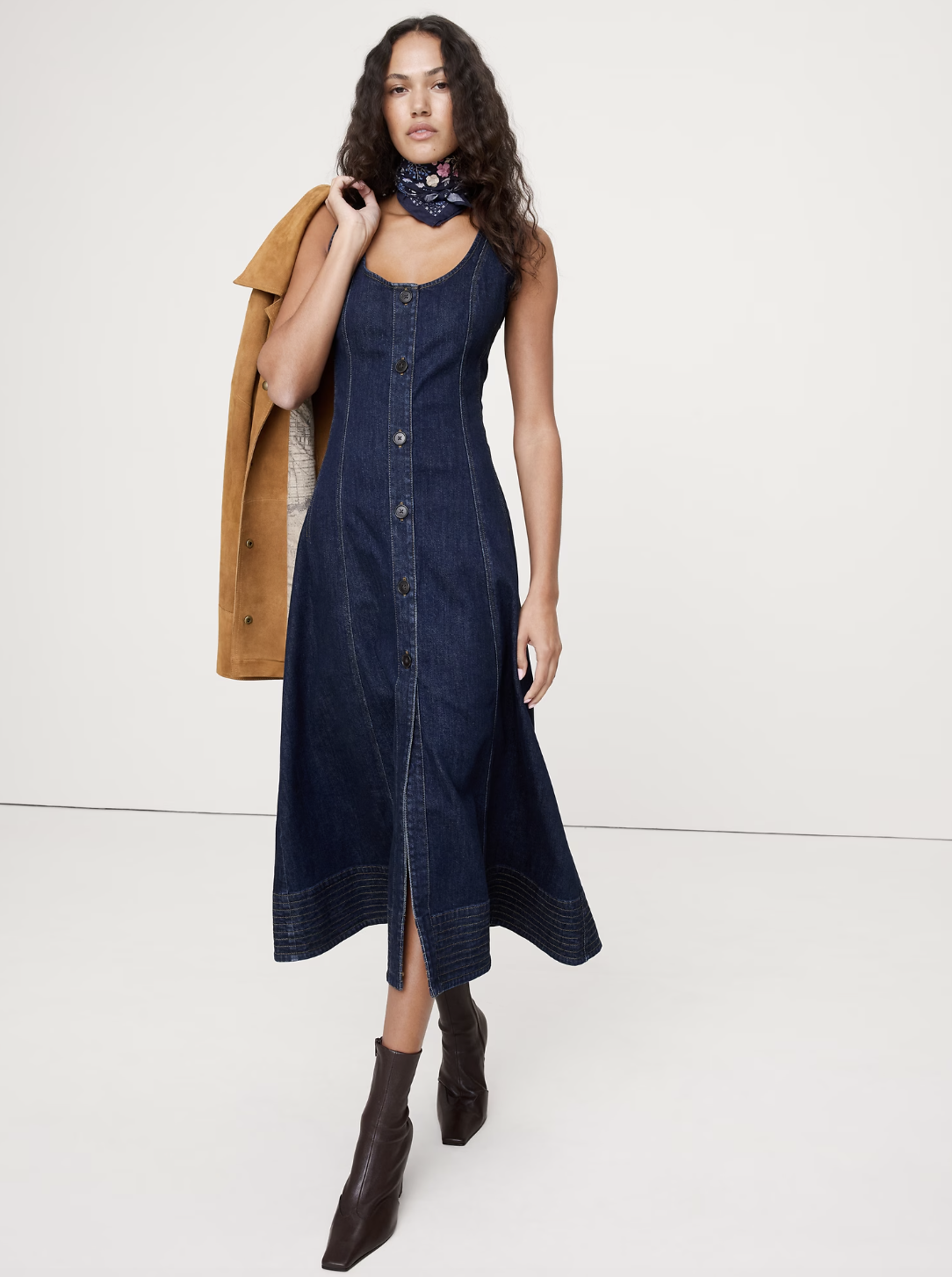 A denim midi dress styled with a structured tan jacket, demonstrating a professional outfit formula that pairs perfectly with sneakers.