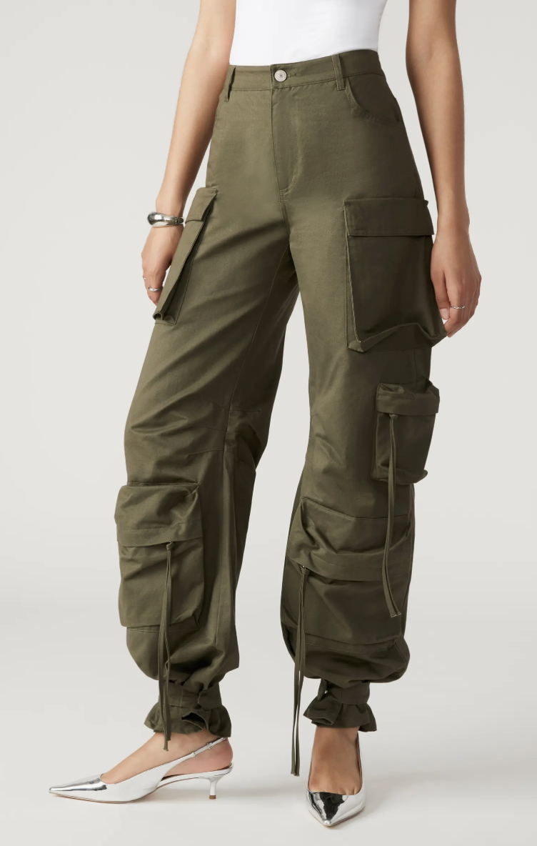 Close up of a woman wearing metallic silver pointed-toe kitten heel slingbacks with olive green cargo pants.