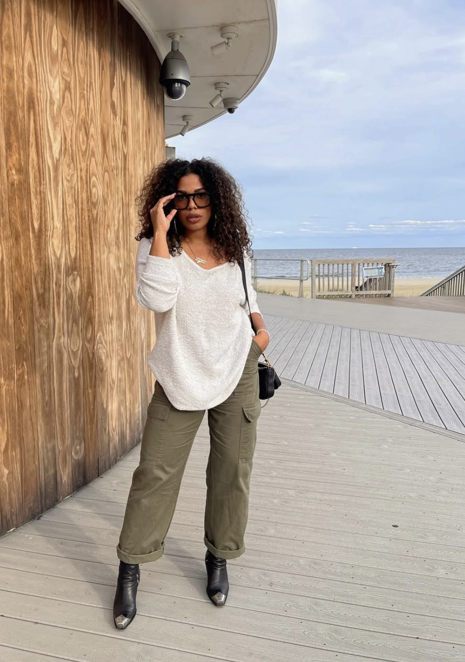 Woman wearing a crisp white t-shirt tucked into olive green trousers with a belt.