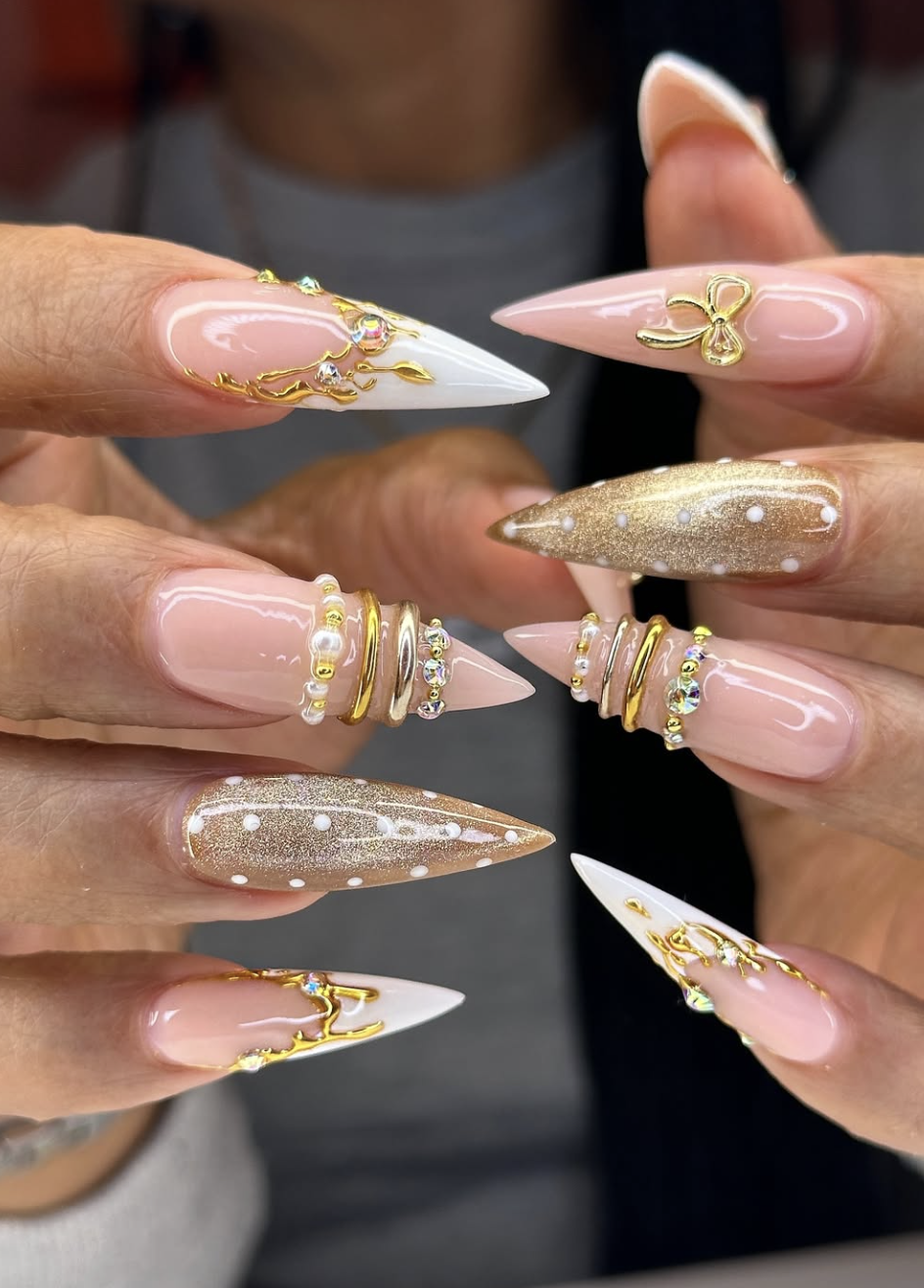 Long almond-shaped milky white nails with 3D gold liquid metal frames and tiny white pearl accents.