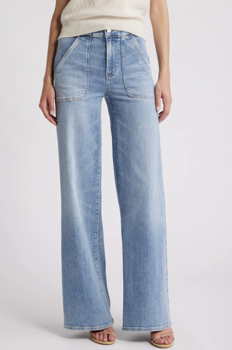 A pair of light blue FRAME wide-leg jeans featuring prominent front patch pockets and a clean hem, styled with brown strappy sandals.