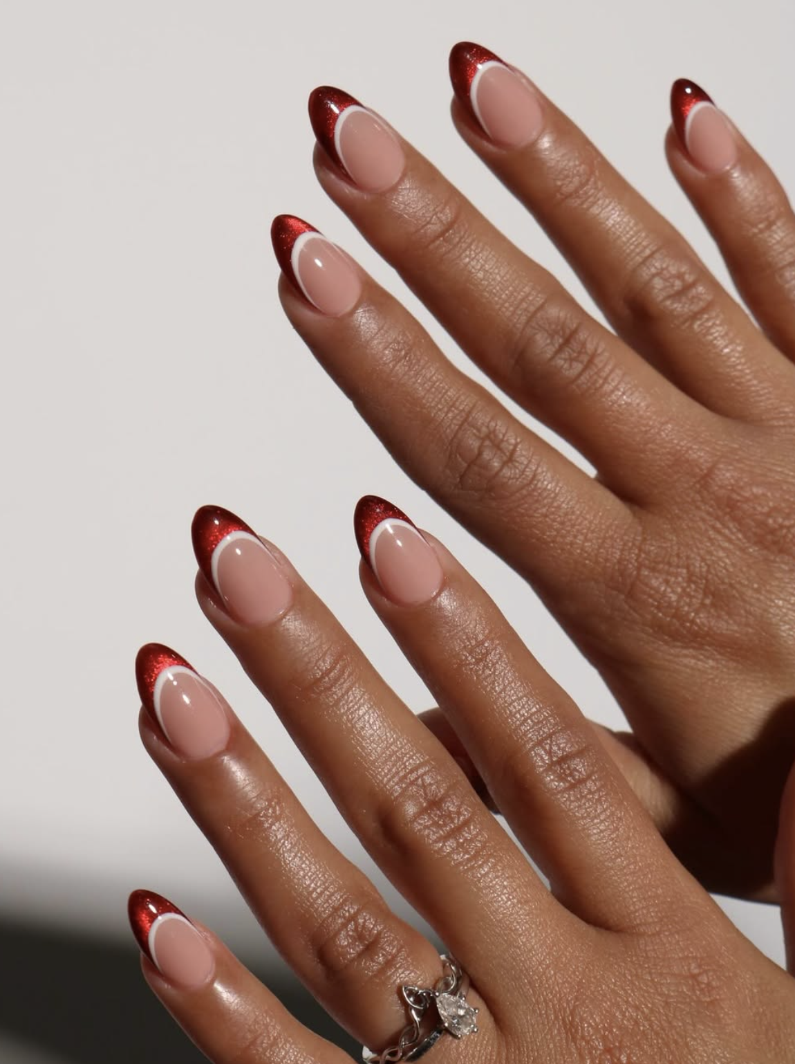 Micro red French tip Christmas nails over a sheer pink base